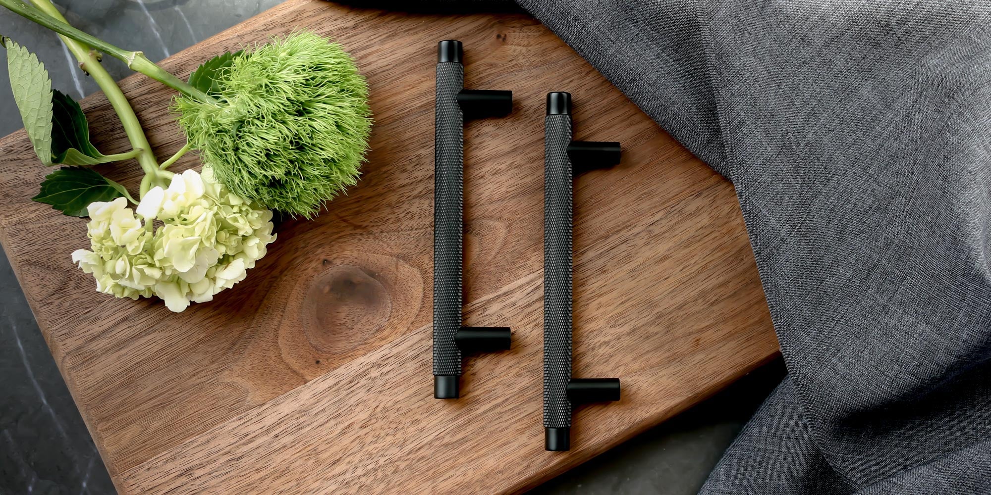 Knurled kitchen cabinet pull in black on a wooden cutting board. Potter and Clay