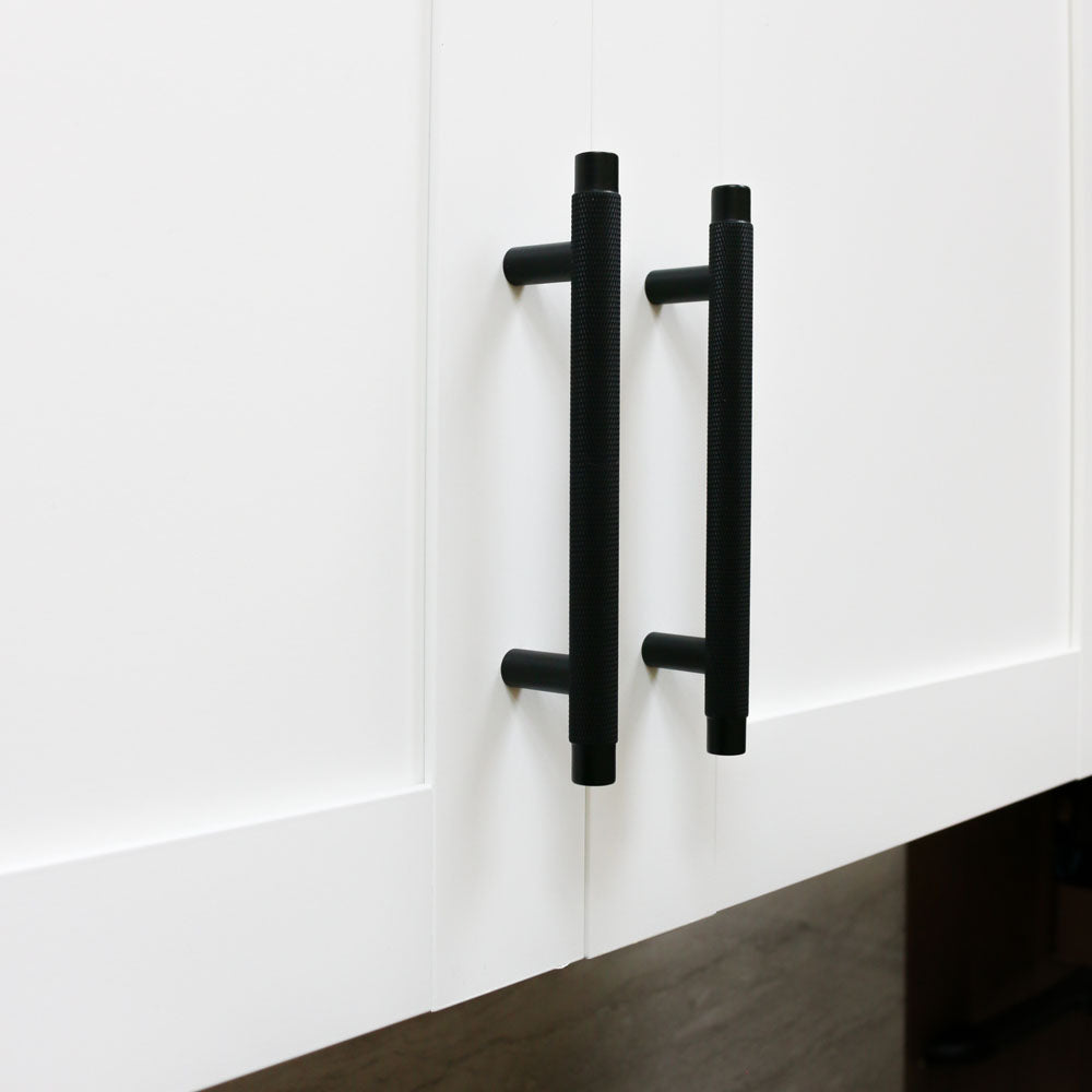 Matte black knurled kitchen cabinet pulls on white shaker cabinets. Potter and Clay