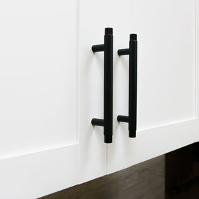 Matte black knurled kitchen cabinet pulls on white shaker cabinets. Potter and Clay